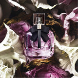 YSL Mon Paris Eau de Parfum 90ml nestled among pink and white petals, emphasizing its romantic floral fragrance profile.